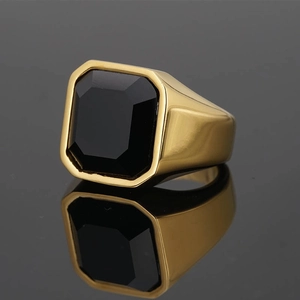 Men's vintage golden signet ring with emerald-cut black gemstone on a reflective surface