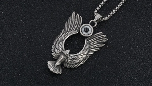 Dettaglio del ciondolo ad ala di aquila con trame metalliche vintage e intarsio turchese