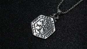 Close-up of Viking Vegvisir compass pendant with Nordic runes on black sand