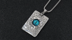 Détail du pendentif œil maléfique vintage avec pupille bleue sur acier texturé rétro