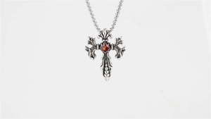 Macro detail of gothic cross pendant with red gem and vintage silver dragon scale texture