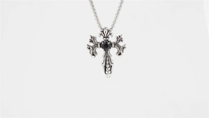 Detail of gothic cross necklace with black stone inlay and embossed pattern