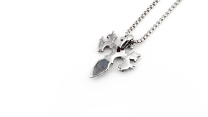 Detail of silver sword pendant with red gemstone and polished stainless steel box chain