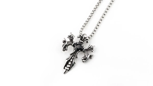 Detailed close-up of gothic cross pendant with black gemstone and vintage relief patterns