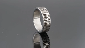 Macro detail of silver adjustable ring featuring rugged tree bark texture on mirror surface