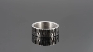 Macro shot of industrial style stainless steel ring with rustic vertical texture and inner engraving