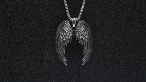 Detailed macro shot of vintage silver wing pendant in punk style on a black background