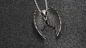 Detailed macro view of an oxidized stainless steel angel wing pendant with intricate feathers
