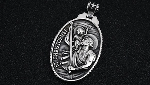 Macro shot of vintage St. Christopher embossed pendant with cross detail and antique finish