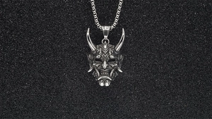 Macro detail of silver Hannya mask pendant with sharp horns and intricate engraving