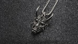 Macro shot of titanium steel Hannya mask pendant with intricate antique silver textures