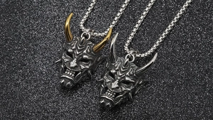 Close-up of vintage Hannya mask pendants with silver and gold accents on box chain