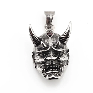 Hannya mask pendant in vintage steel with inlaid red garnet, centered on white background