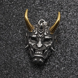 Hannya mask pendant with golden horns and vintage silver finish on black sand background