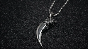 Detailed view of the wolf head and polished tusk pendant on a silver box chain