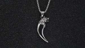 Detailed macro view of retro wolf fang pendant in polished stainless steel for men