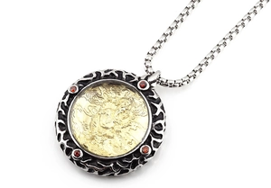 Detalle de un colgante vintage de plata y oro con circón rojo y relieve grabado