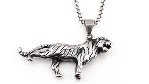 Macro view of a 3D embossed silver tiger pendant with a box chain and vintage metal texture