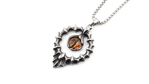 Gros plan d'un collier pendentif oeil de dragon gothique avec pupille orange et pointes