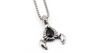 Detail of scorpion pendant necklace featuring oval black stone and stainless steel box chain