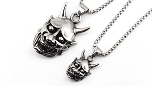Macro detail of vintage stainless steel Hannya mask pendants in two sizes with box chains