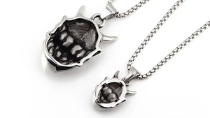 Macro detail of two silver Prajna demon mask pendants with intricate vintage textures