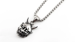 Macro detail of retro stainless steel Hannya mask pendant with antique finish and box chain
