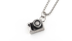 Detailed close-up of a retro silver camera pendant with vintage oxidized metal texture