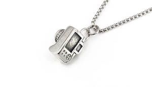 Macro detail of retro mini camera pendant featuring intricate buttons and textured lens dial