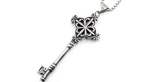 Détail macro du pendentif clé rétro avec étoile gravée et chaîne maille vénitienne