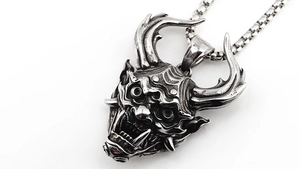 Macro d'un pendentif masque de démon punk gothique en acier argenté vintage avec chaîne