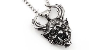 Macro d'un pendentif masque Hannya punk en acier inoxydable vintage avec détails de crâne