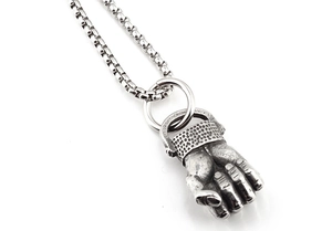 Detail of vintage silver fist pendant with box chain and oxidized punk textures