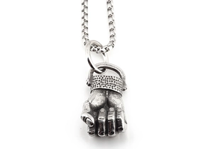 Macro detail of vintage silver fist pendant with honeycomb pattern on box chain necklace