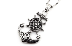 Macro shot of vintage nautical anchor and helm pendant with antique finish on box chain