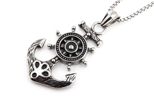Macro shot of vintage steel nautical anchor and helm pendant with antique wood texture