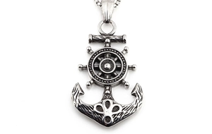 Close-up of vintage pirate anchor and helm pendant in silver steel with textured details