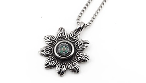 Macro view of vintage silver compass pendant with radiating flame pattern on chain