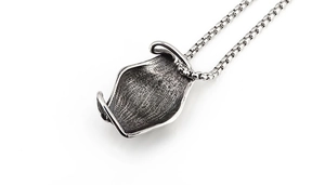 Détail macro du pendentif en forme de briquet argenté vintage avec textures rock rétro