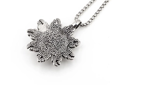 Macro detail of sunflower pendant back with antique silver texture and box chain