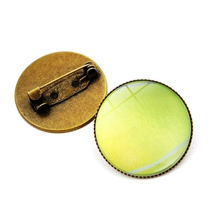 Detailed view of tennis glass dome brooches with vintage bronze pins and athletic theme