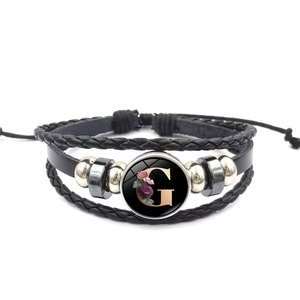 Detail van de meerlaagse leren armband met letter G en verstelbaar gevlochten touw
