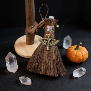 Mini Wicca witch broom with rose quartz and a bronze goddess charm on a dark background