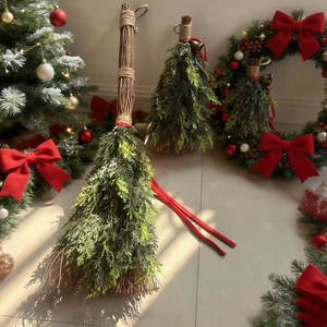 Detail of pine needle Christmas broom with red ribbon bow and golden bell decoration