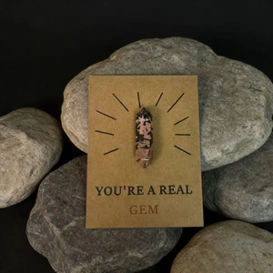 Macro detail van Rhodoniet kristalpunt op een YOU'RE A REAL GEM kraft cadeaukaart