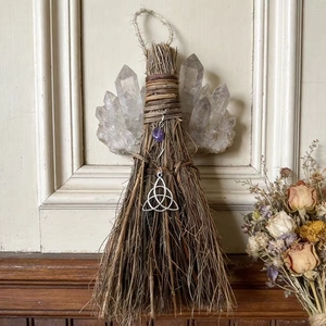 Detail of a handmade witch besom with white crystal and silver Celtic Knot pendant