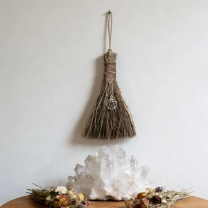 Detail of handmade decorative straw witch broom with pink crystal and pentagram charm