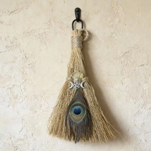 Macro shot of witch besom featuring yellow crystal, pentagram symbol, and peacock feather