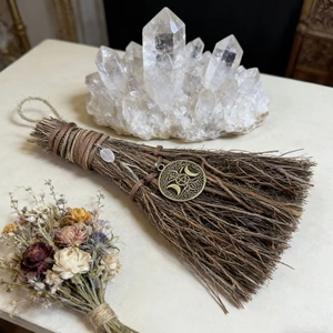 Macro detail of handmade mini witch broom with bronze moon charm and pink crystal stone