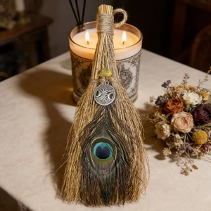 Detail of handcrafted witch broom with peacock feathers and Celtic moon pendant